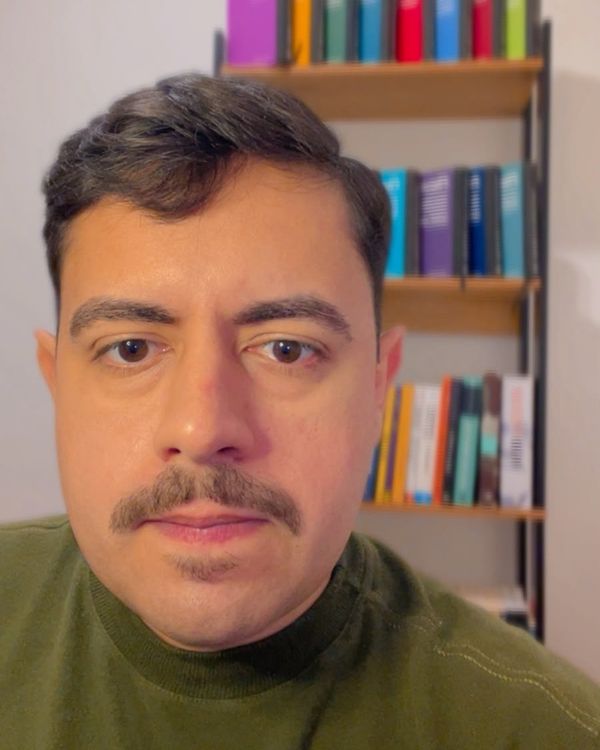 Gustavo Sales no consultório, diante da estante de livros